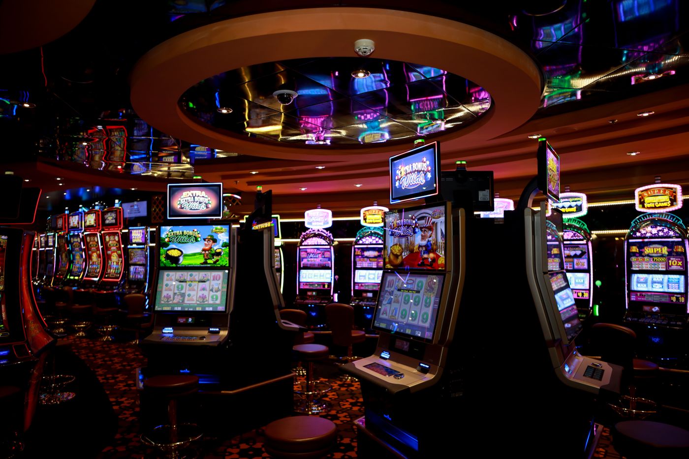 Suasana lantai kasino modern dengan deretan mesin slot menyala